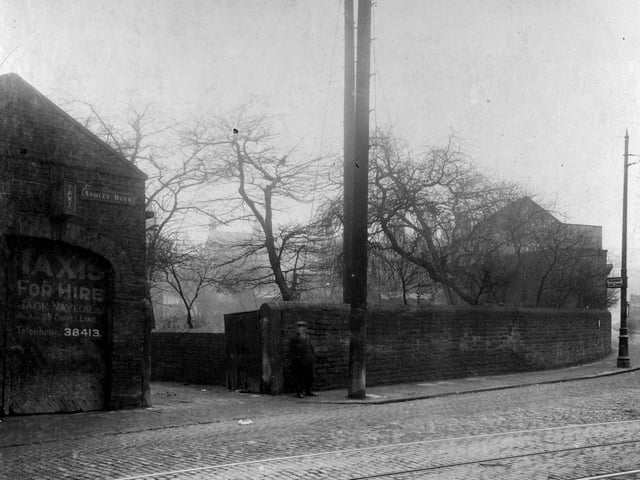 Armley Road at the junction with Crab Lane in February 1929. A man is outside the entrance to 'Taxis for hire', owned by Jack Naylor. Tram stop on the corner with sign on lamp post stating 'Tramway fare Stage'. Cobbled road with tramlines along Armley Road.