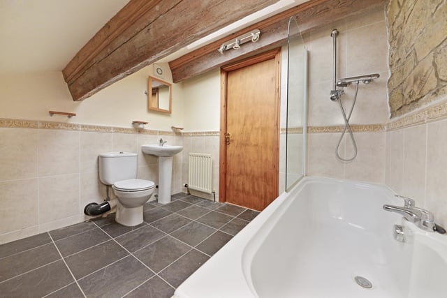 This bathroom suite includes a deep bath with overhead shower unit.