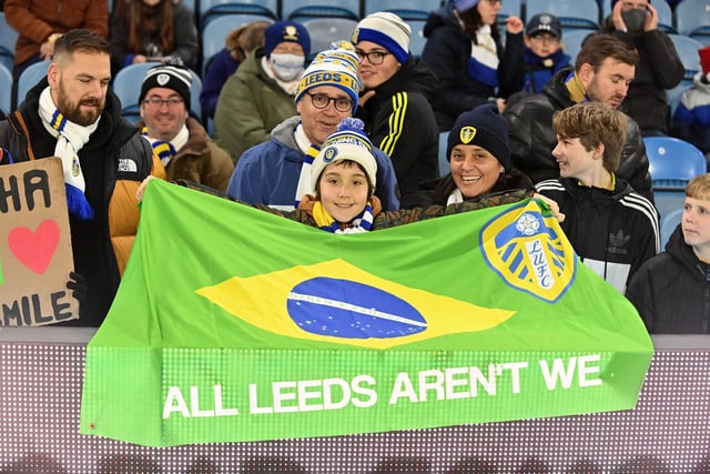 A young Leeds United fan waving a flag for Raphinha.
