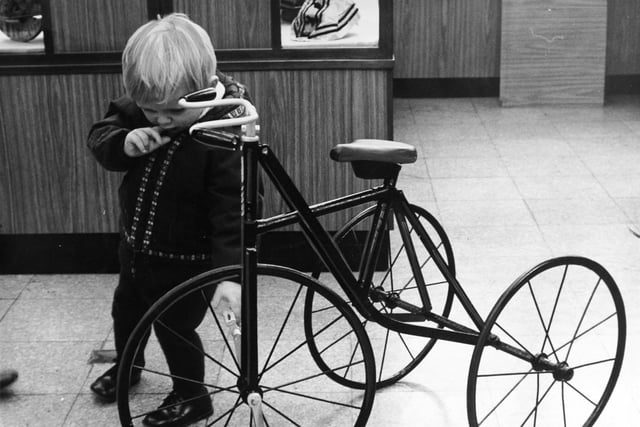 Dare he ride it? Two-year-old Timothy Adamson makes a cautious assessment of a vintage tricycle at a Christmas exhibition of 'Yesterday's Toys' at Leeds City Museum in 1970.