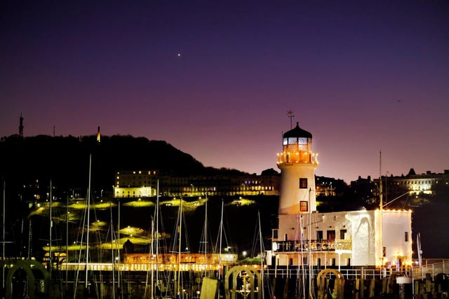 Scarborough Lighthouse shines and twinkles in the evening sky.