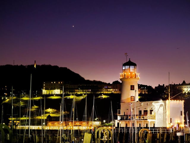 Scarborough Lighthouse shines and twinkles in the evening sky.