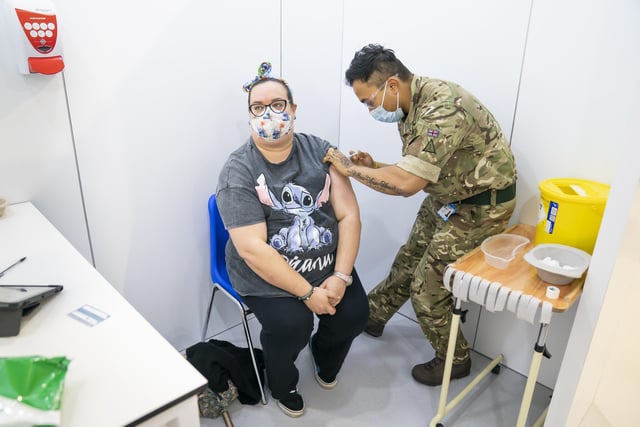 A member of the Armed Service (right) administers a booster coronavirus vaccine to Charlotte Daniel (left)
