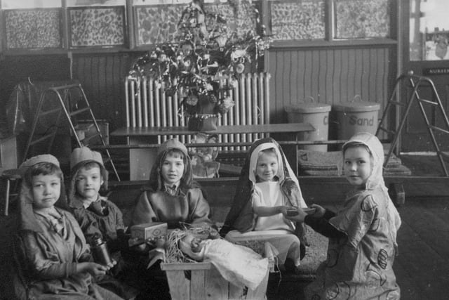Children in a scene from a Nativity play at . A doll representing baby Jesus lies in a small straw-filled crib, whilst three children dressed as the Wise Men are presenting gifts to two dressed as Mary and Joseph. A decorated Christmas tree can be seen in the background. Bentley Lane School was built in the early 1930s, and closed in 2004.