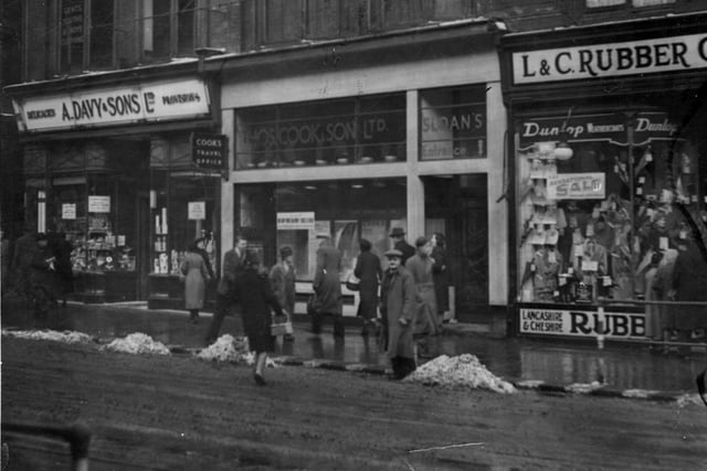 Boar Lane in February 1940. Pictured, from left, is  Arthur Davy & Sons Ltd, grocers, Thomas Cook Travel Office, Entrance Outfitters (which can be seen above), then Lancashire and Cheshire Rubber Company, waterproof clothing manufacturers.