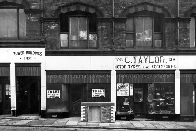Albion Street in December 1940. Pictured is Tower Buildings, then C. Taylor, Motor Tyres and Accessories, with goods in shop window. A small brick structure with wooden door is also in view. Purpose unknown.