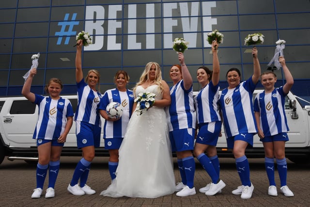 Bride Zoe Baxter with her seven bridesmaids dressed in full Wigan Athletic kit, after their dresses didn't arrive from Vietnam - pictured outside The DW Stadium, Wigan, as she married Neil Harrison.