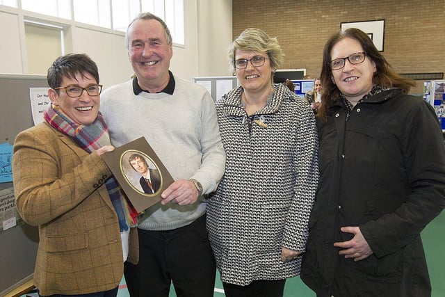 Former janitor John Currie proudly shows an old photograph of him at work to his daughters Jennifer, Susan and Christine.