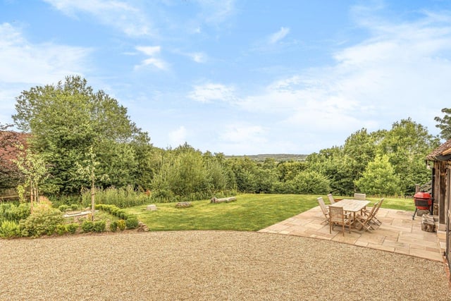 large paved patio adjacent to the house leads to a large lawn garden.