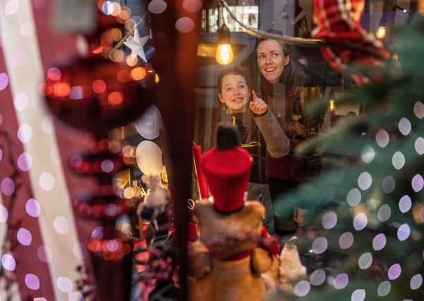 A woman and daughter looking through the window of The Upholsterer on North Street during late night shopping in Midhurst, Sussex. Photograph by Christopher Ison © 07544044177 chris@christopherison.com www.christopherison.com. SUS-201216-115817001