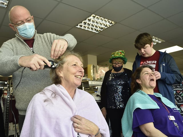 Sue Reeves (dark hair) and Debbie Gibbs (light hair) from the East Anglian Childrens' Hospice charity shop , Whittlesey taking part in a charity head shave. Cutting the hair are Steve Gibbs and Jamie Reeves (14) EMN-201217-144044009