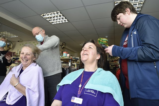 Sue Reeves (dark hair) and Debbie Gibbs (light hair) from the East Anglian Childrens' Hospice charity shop , Whittlesey taking part in a charity head shave. Cutting the hair are Steve Gibbs and Jamie Reeves (14) EMN-201217-144106009