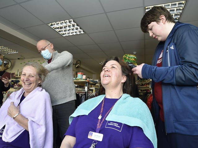 Sue Reeves (dark hair) and Debbie Gibbs (light hair) from the East Anglian Childrens' Hospice charity shop , Whittlesey taking part in a charity head shave. Cutting the hair are Steve Gibbs and Jamie Reeves (14) EMN-201217-144106009