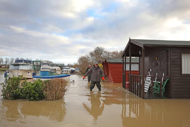 People wade through floodwater to check boats and property at Orton . Picture: Paul Marriott