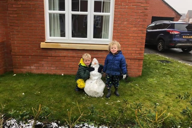 Brothers, Samuel aged 6, and Hugo aged 4, stand proudly next to their snowman in Kineton