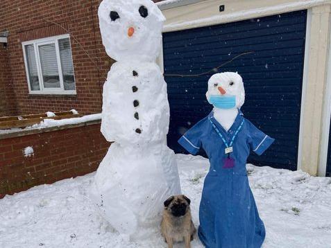 An NHS snow nurse with a snow man and a snowy dog in Little Harrowden, Wellingborough. Photo: Simon Curran