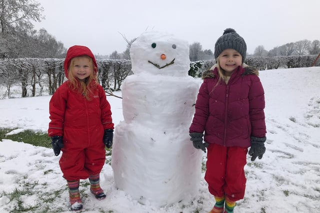 Heidi and Katie Mitchell (3 and 6) with the snowman they built in their garden with the help of their mum and dad Ellie and Colin.