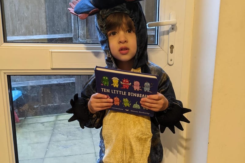 Little three-year-old Sam has dressed up as a dinosaur while holding his favourite book, 'Ten Little Dinosaurs'.