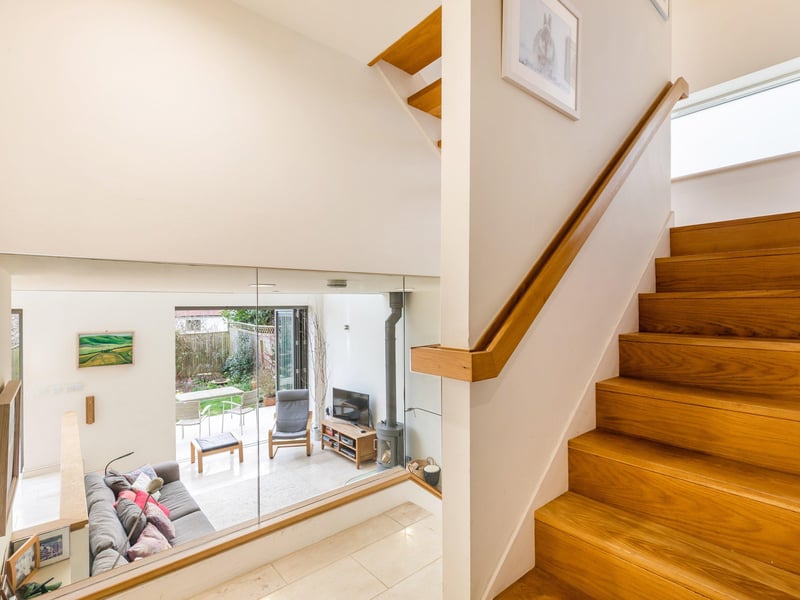 Stairs rising to first floor and steps leading down either side of the entrance hall to the open plan kitchen, living and dining area.