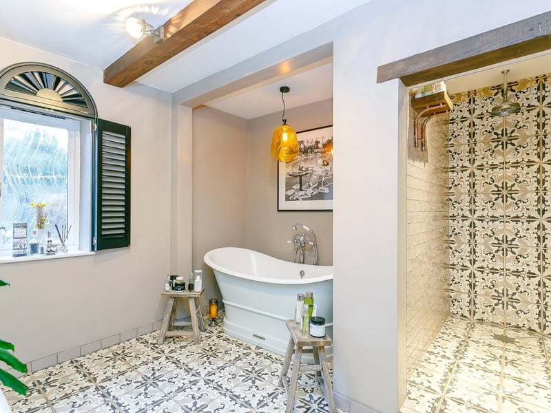 A spacious Fired Earth family bathroom with walk-in shower and free standing bath.