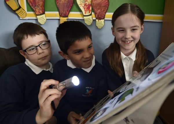 Year 3/4  children at Nene Valley Primary School reading with a torch because all lights were turned off for Climate Action Day EMN-200403-170317009