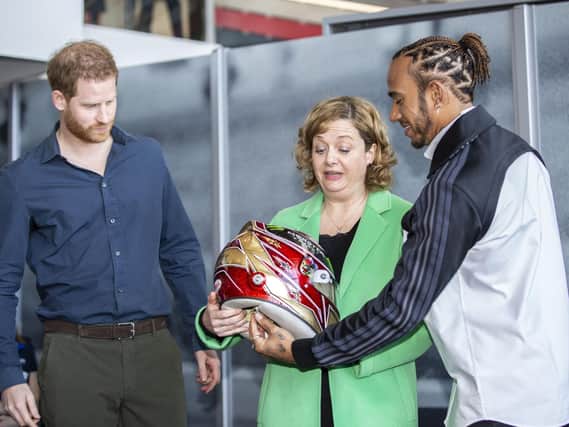 The Silverstone Experience chief executive Sally Reynolds accepts Lewis Hamilton's 2019 helmet alongside Prince Harry