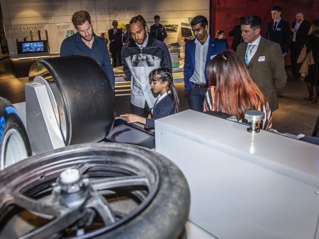 Schoolchildren explain the various displays at The Silverstone Experience to Prince Harry and Lewis Hamilton