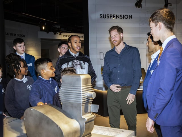 Schoolchildren explain the various displays at The Silverstone Experience to Prince Harry and Lewis Hamilton