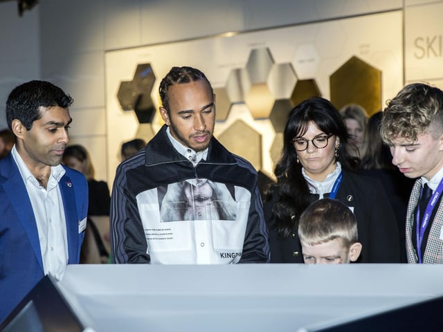 Schoolchildren explain the various displays at The Silverstone Experience to Lewis Hamilton and ex-F1 driver Karun Chandhok