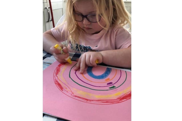 Joanna Morgan's daughter drawing a rainbow to put in the window for other children to find SUS-200322-143240001