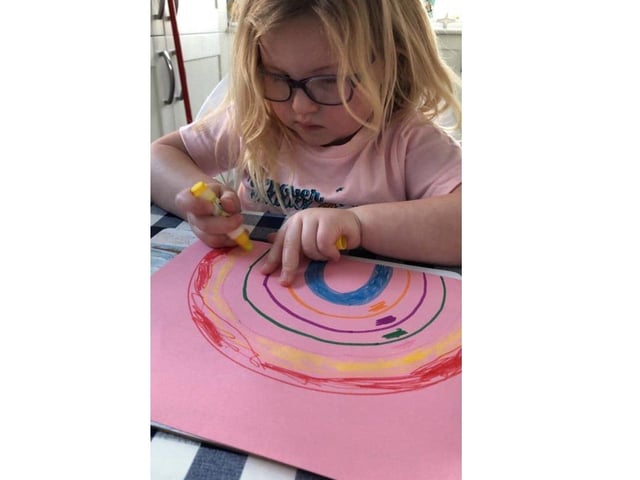 Joanna Morgan's daughter drawing a rainbow to put in the window for other children to find SUS-200322-143240001