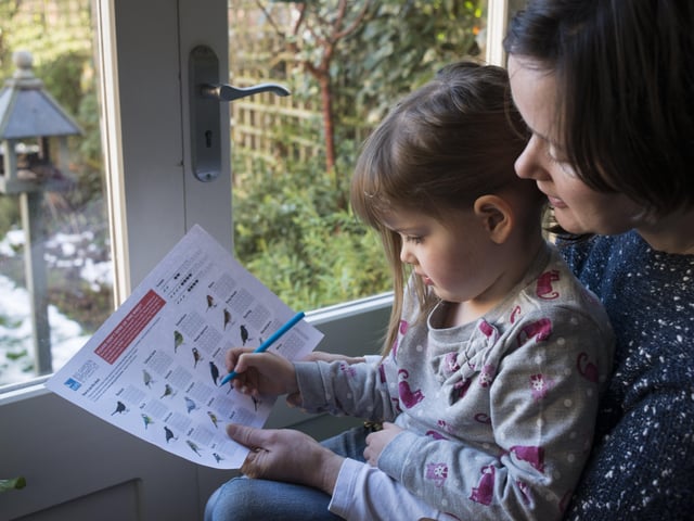 RSPB Big Garden Birdwatch. Mother and her daughter counting birds in their garden, Bedford, UK, January 2013 SUS-200204-092759001