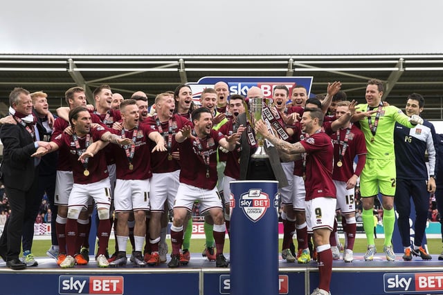 The team are all on the podium and the trophy is handed to Cobblers skipper Marc Richards