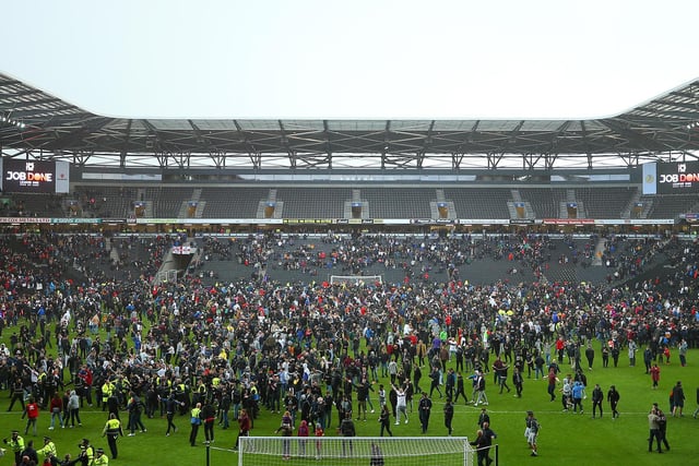 Fans on the pitch celebrating promotion