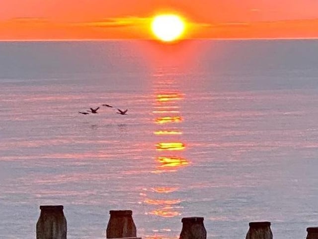 Sunrise over Eastbourne beach by John Smalley. SUS-200705-091812001