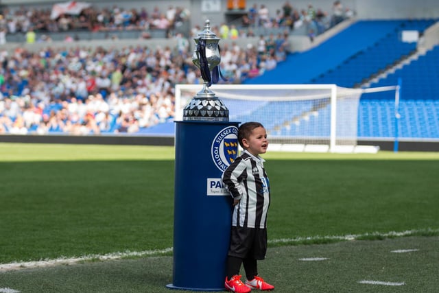 A young Peacehaven fan stands with the trophy