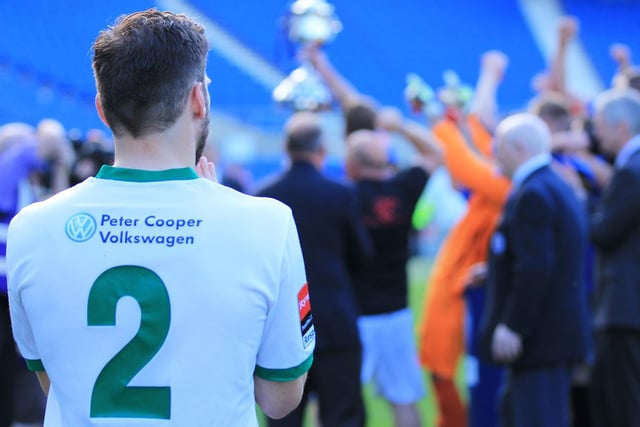 A Bognor player watches on as Peacehaven lifts the cup