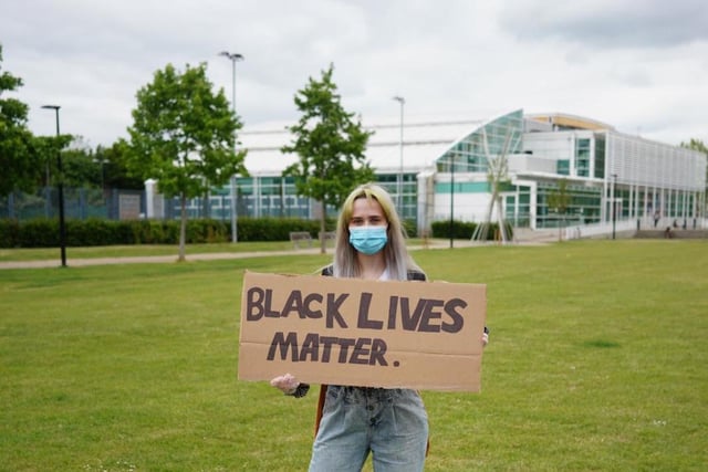 A campaigner carrying a placard and wearing a face covering