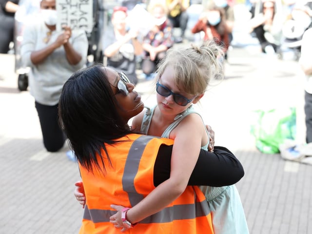 Summer Ogden-Friel , eight, gives speaker Amal Abshir a hug during the eight-minute kneel