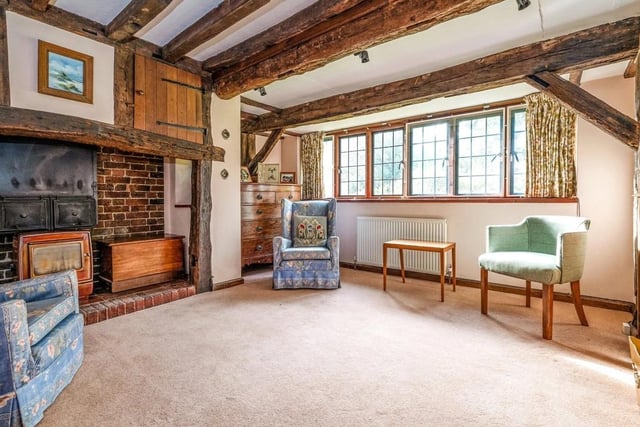 There is a large sitting room with an ornate wooden fireplace and triple bay windows that overlook the gardens. Picture: Jackson-Stops Lindfield.