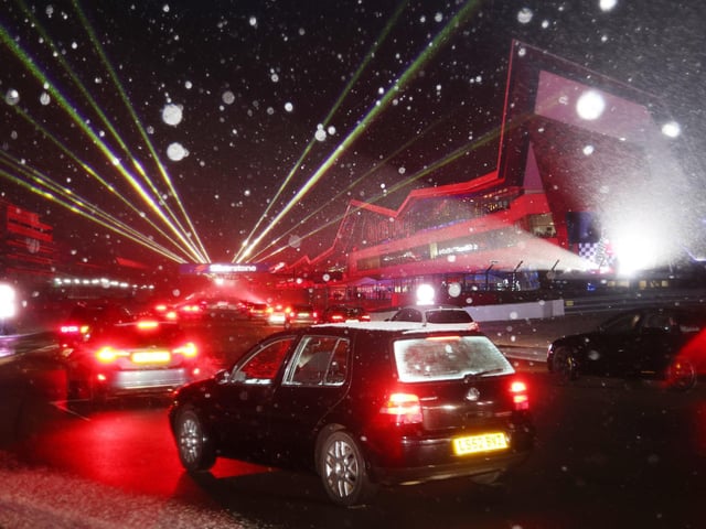 Snowflakes danced in the lights as cars hit the track