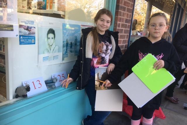 Annabelle Smalley (11) and Louisa Hamilton (9) with sheep hiding in the Pharmacy 
window