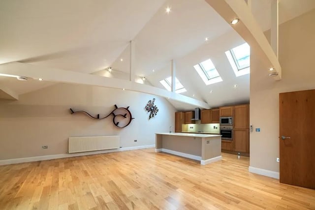 There is a vaulted ceiling with exposed beams and a range of Velux skylight windows
