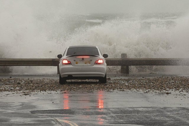 Selsey seasfront gets a lashing from storm 'Barra' as one car takes a close up look. By Chris Hatton SUS-210812-084432003