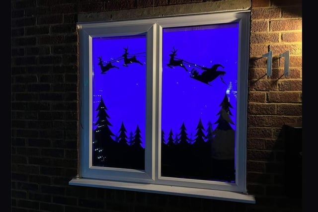Santa is flying through the sky with his reindeer in this window
