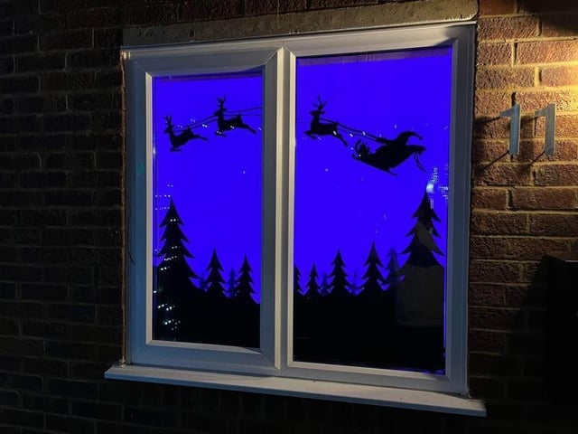 Santa is flying through the sky with his reindeer in this window