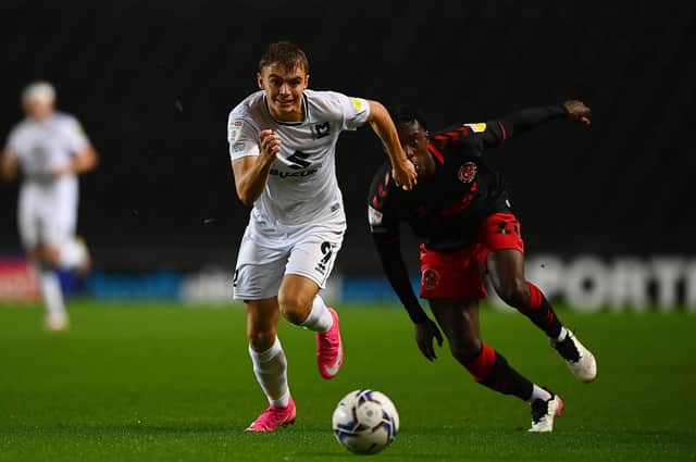 Scott Twine of MK Dons (left) is challenged by Jay Matete of Fleetwood Town (Photo by Clive Mason/Getty Images).