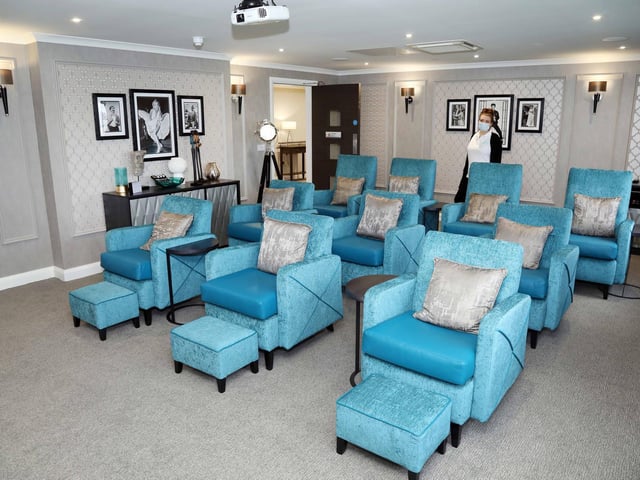 The home's cinema that has a popcorn machine ten recliner chairs