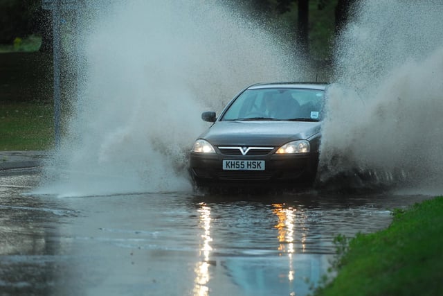 A driver navigates a huge puddle on Thorpe Road during heavy rain.