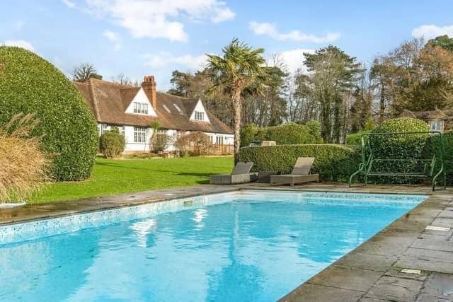 There is a swimming pool in the garden with paved surround, a timber pool hut and a thatched breeze house. Picture: Savills - Haywards Heath.